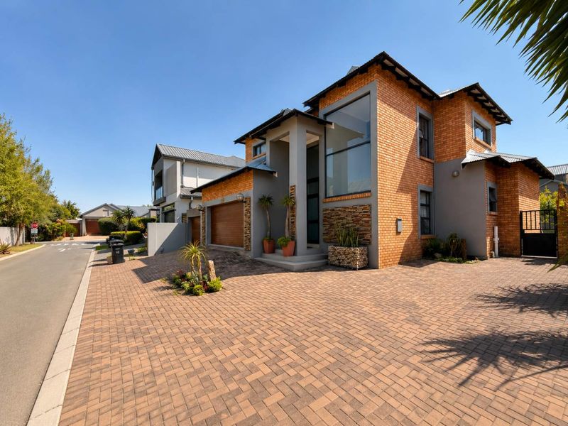 Modern double-storey residential home featuring a brick and stone facade, paved driveway, and integrated double garage in a well-maintained street setting.