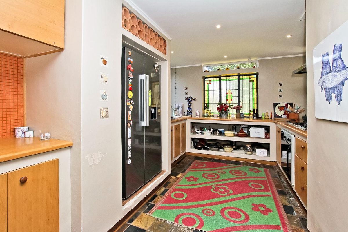 A functional kitchen featuring built-in cabinetry, a dedicated fridge alcove with overhead storage, stone-tiled flooring, and a decorative leaded glass window.