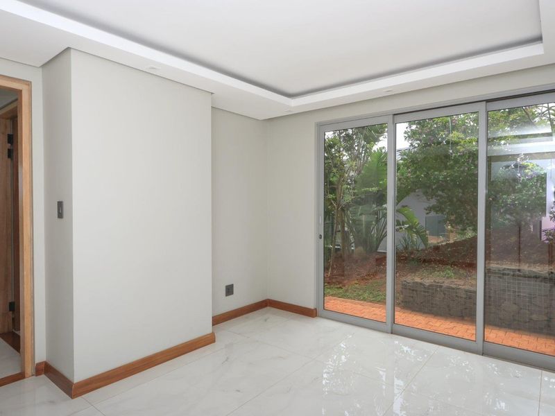 Bright, modern living area featuring large sliding glass doors, polished porcelain tile flooring, and a clean, minimalist aesthetic with recessed ceiling detail.