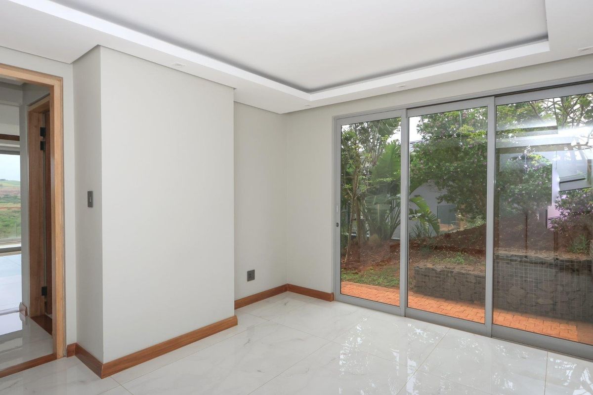 Bright, modern living area featuring large sliding glass doors, polished porcelain tile flooring, and a clean, minimalist aesthetic with recessed ceiling detail.