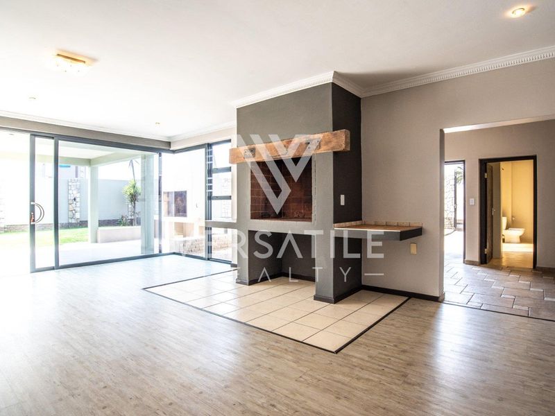 Spacious living area featuring a built-in fireplace with a wooden mantel, large sliding glass doors, and neutral tiled flooring throughout.