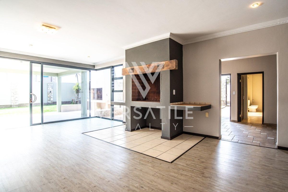 Spacious living area featuring a built-in fireplace with a wooden mantel, large sliding glass doors, and neutral tiled flooring throughout.
