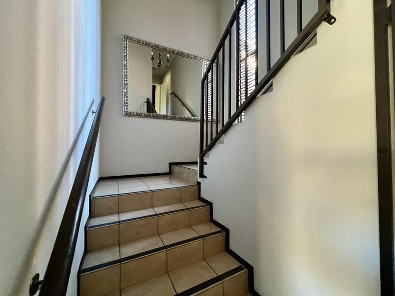 A staircase featuring tiled steps, a metal balustrade, and a handrail, providing access between levels in this townhouse.