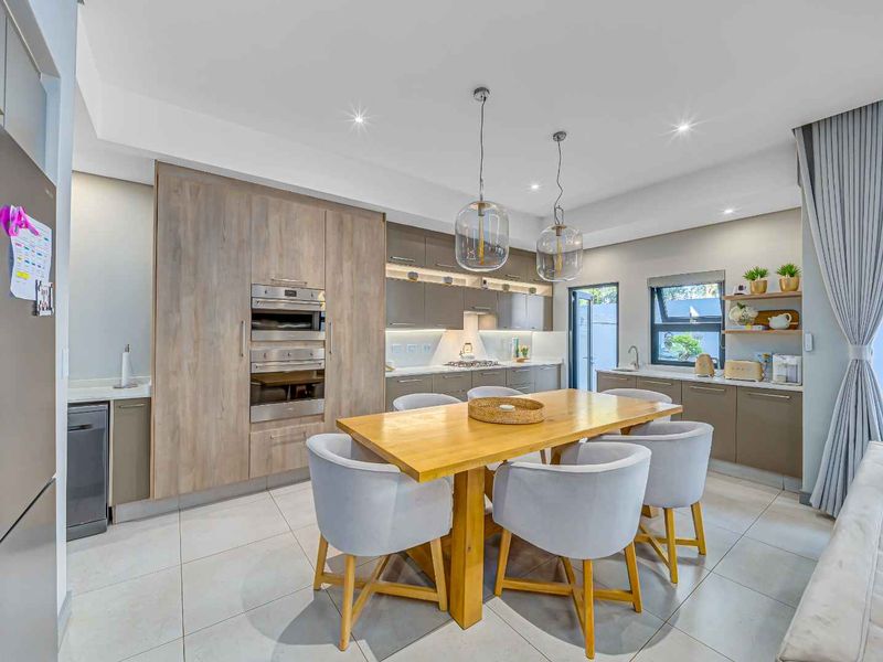 Modern open-plan kitchen featuring sleek wood-tone cabinetry, stone countertops, integrated appliances, and high-quality porcelain floor tiles, seamlessly flowing into the living area.