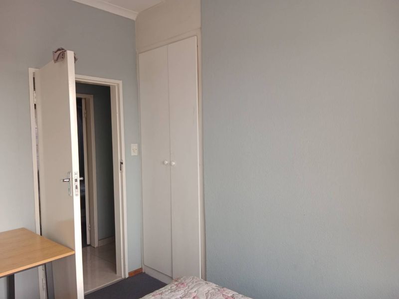 A bedroom featuring a built-in cupboard and neutral wall finishes, providing a functional space with potential for cosmetic updates.