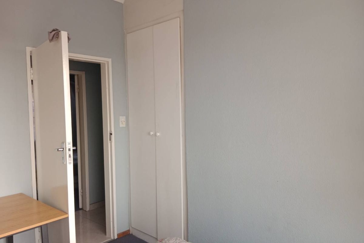 A bedroom featuring a built-in cupboard and neutral wall finishes, providing a functional space with potential for cosmetic updates.