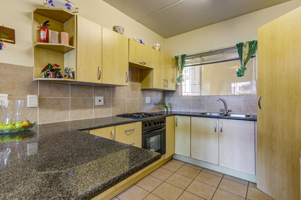 Functional kitchen featuring light wood-tone cabinetry, granite countertops, a built-in oven with gas hob, and tiled flooring.