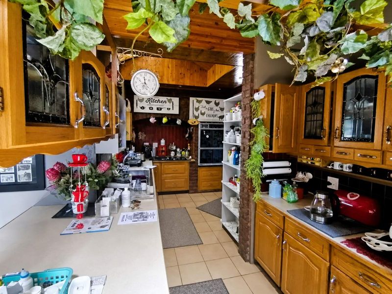 Traditional kitchen featuring extensive wooden cabinetry, built-in oven, cooktop, and exposed timber ceiling beams with a functional layout.