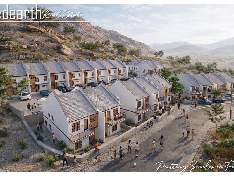 An aerial perspective of a modern townhouse development featuring multiple units with pitched roofs, balconies, and integrated paved driveways in a scenic landscape.