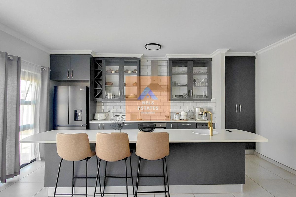 Modern kitchen featuring dark cabinetry, a central island with a brass faucet, subway tile backsplash, and integrated storage solutions.
