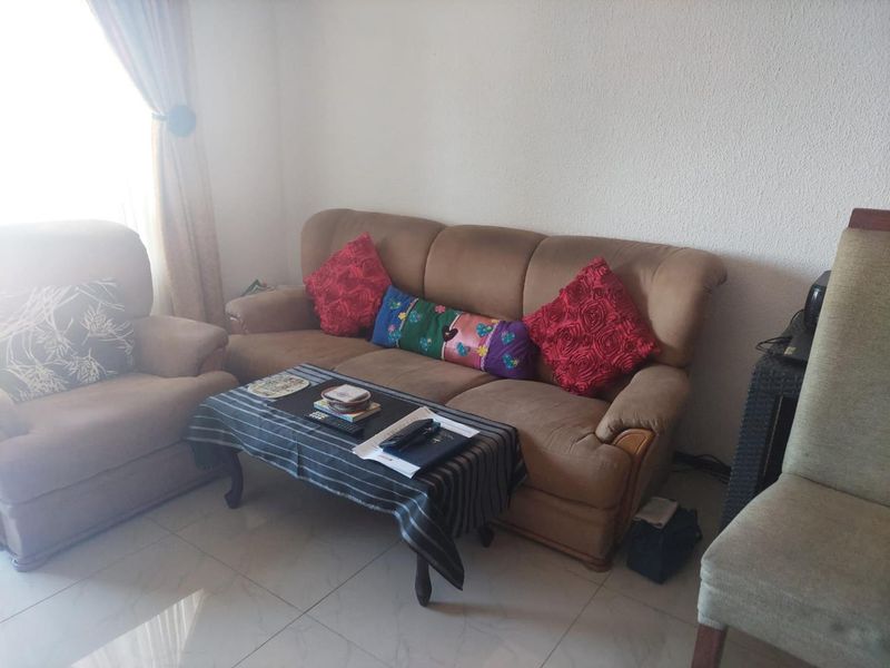 A living room area featuring tiled flooring and natural light from a window.