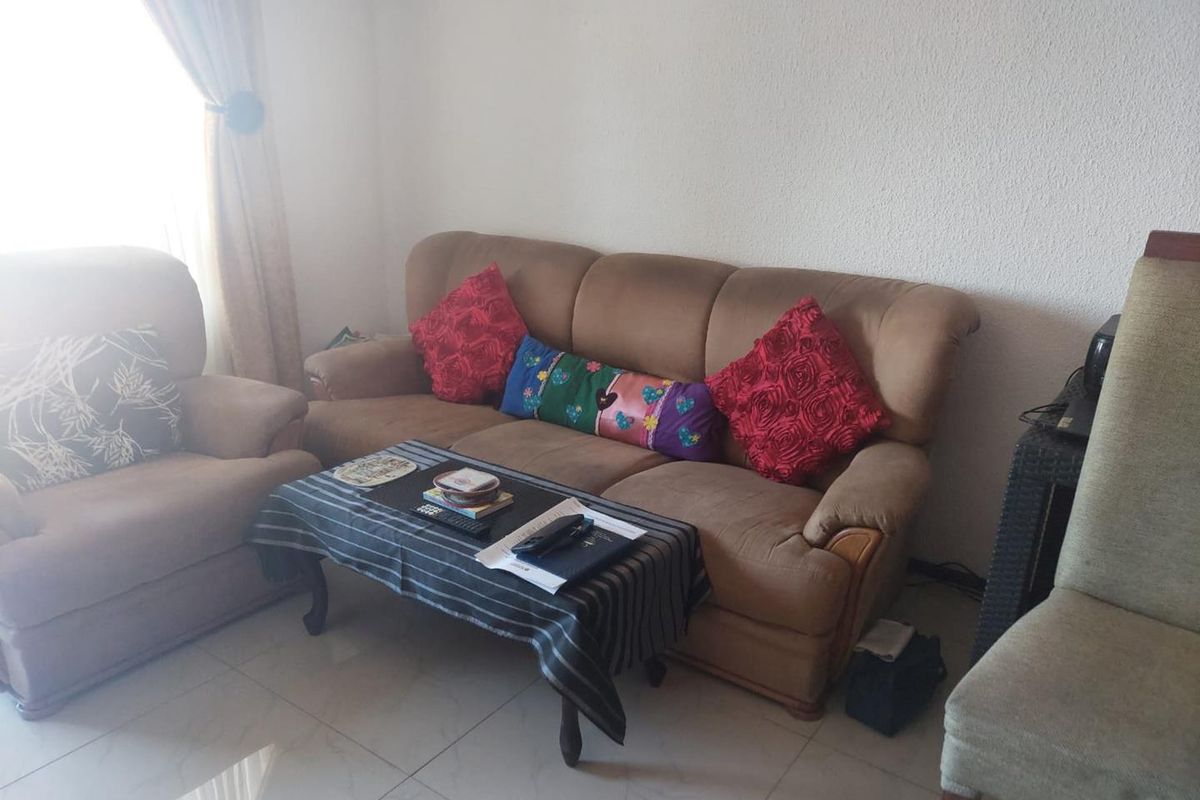 A living room area featuring tiled flooring and natural light from a window.