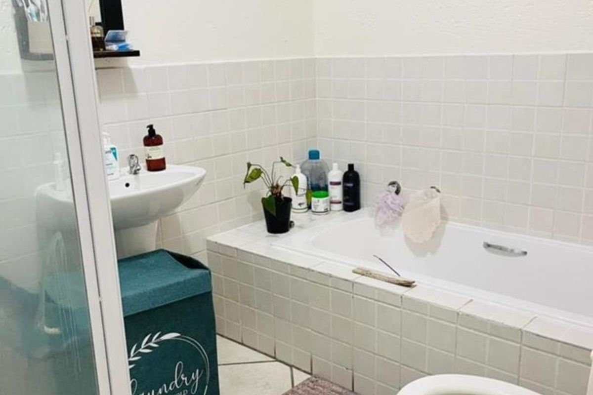A functional bathroom featuring a built-in bathtub, pedestal sink, and a separate shower enclosure with white wall tiling.