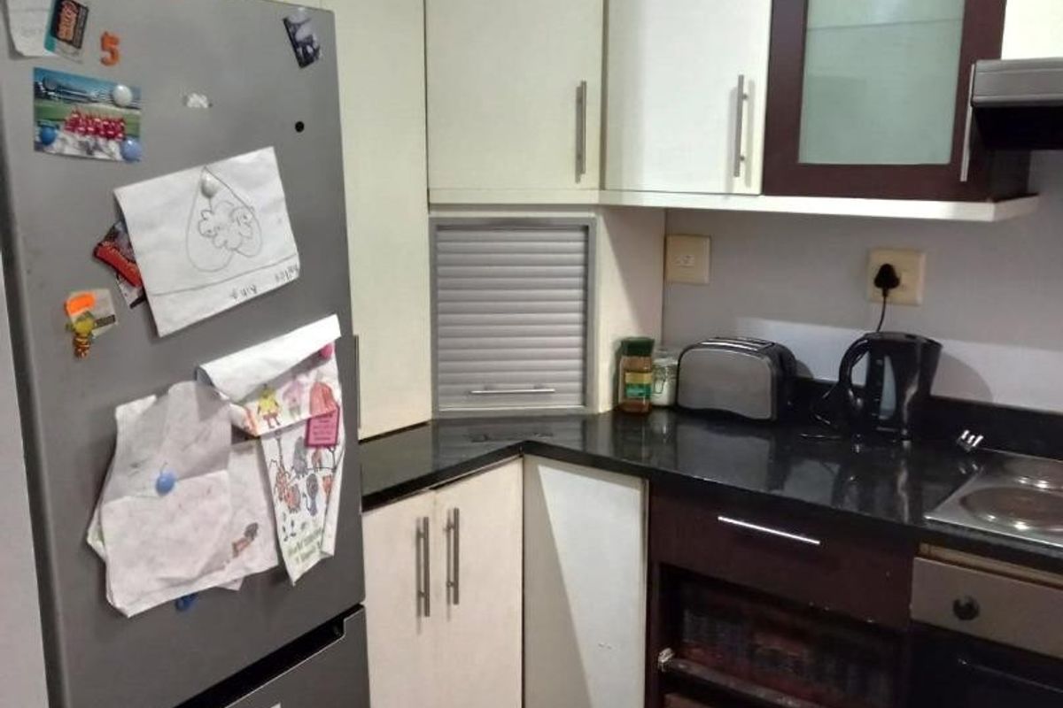 Compact kitchen featuring two-tone cabinetry, granite countertops, built-in oven, hob, and a convenient corner appliance garage for organized storage.