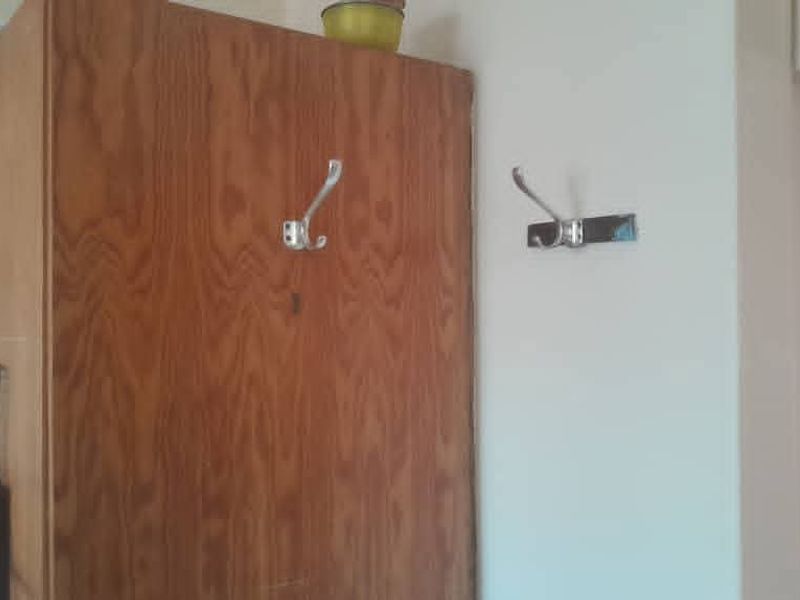 A functional hallway area featuring built-in wooden cabinetry and wall-mounted coat hooks for storage.