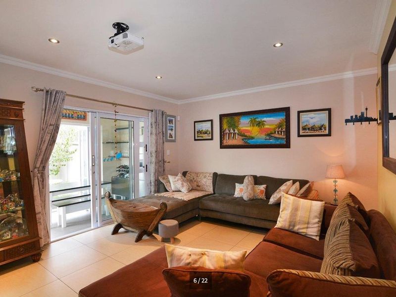 A comfortable living room featuring tiled flooring, recessed downlighting, and a sliding glass door providing access to the outdoor patio area.