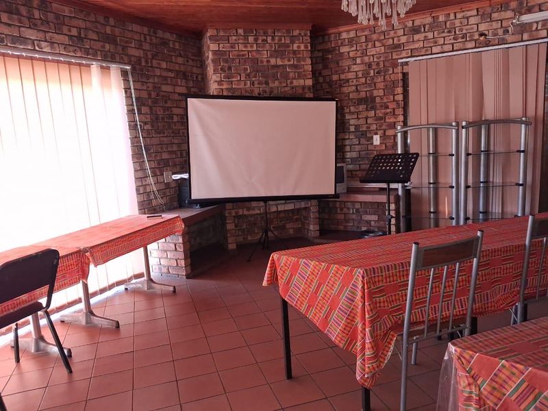 A living area featuring exposed brick walls, tiled flooring, and a timber ceiling, centered around a built-in brick fireplace.