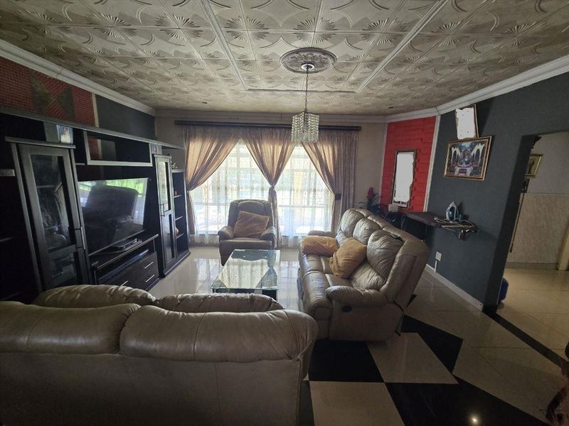 Living room featuring tiled flooring, decorative ceiling tiles, and a sliding glass door providing natural light.