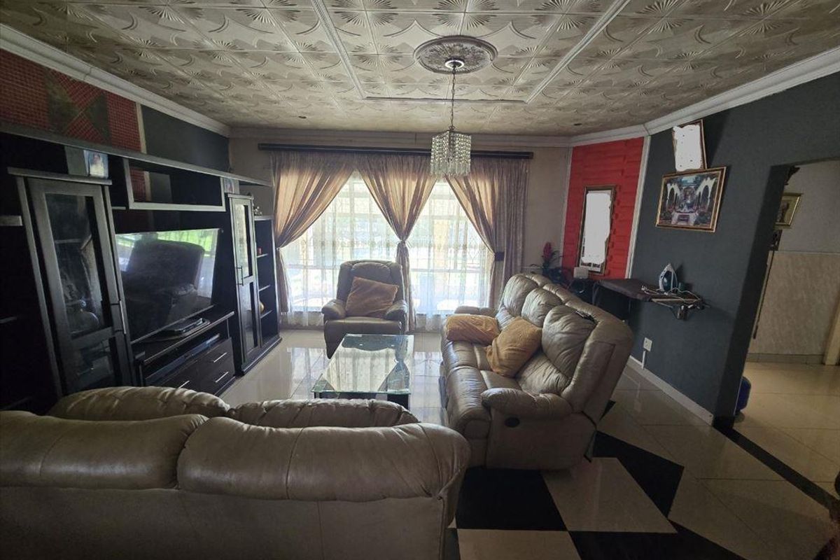 Living room featuring tiled flooring, decorative ceiling tiles, and a sliding glass door providing natural light.