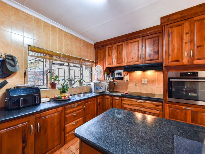 A functional kitchen featuring solid wood cabinetry, granite countertops, a built-in oven, and a tiled backsplash with ample storage space.