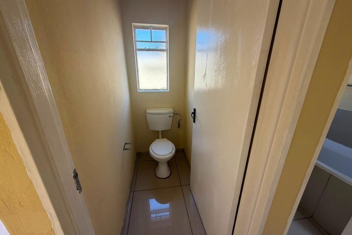 A compact, functional bathroom featuring tiled flooring and a standard toilet, providing a clean and simple utility space.