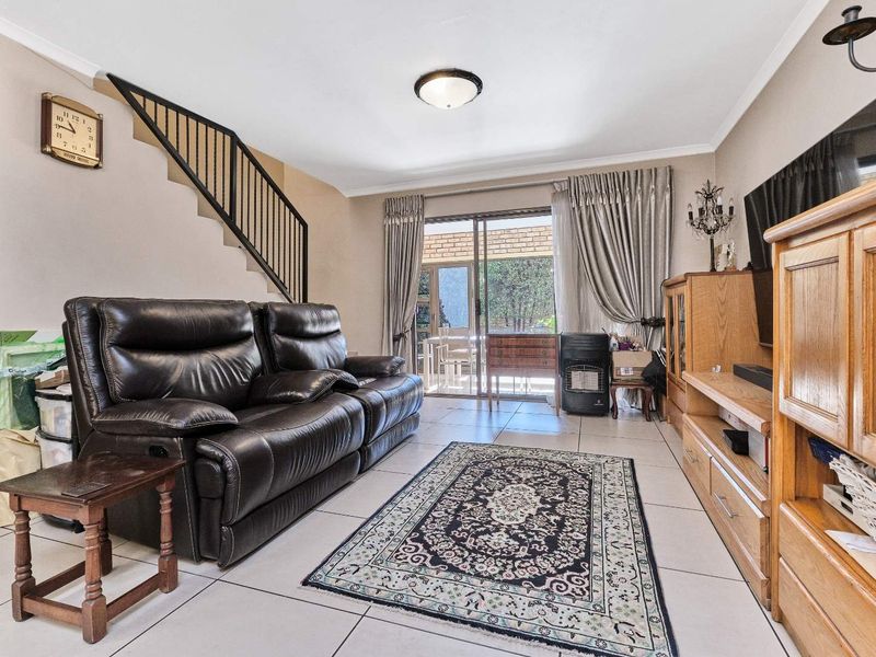 Spacious living room featuring tiled flooring, a staircase with a metal balustrade, and sliding glass doors providing access to the outdoor area.