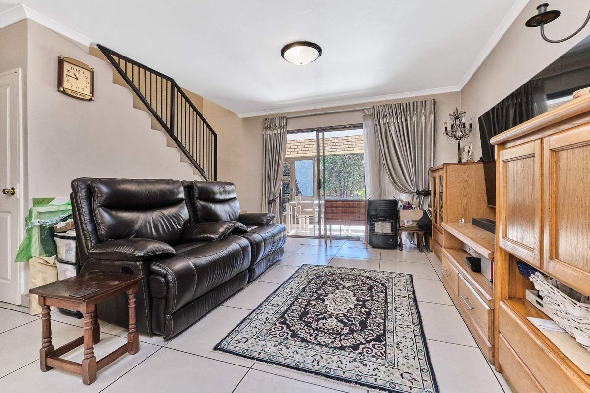 Spacious living room featuring tiled flooring, a staircase with a metal balustrade, and sliding glass doors providing access to the outdoor area.