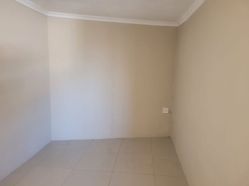 An empty bedroom featuring neutral painted walls, tiled flooring, and coving detail, providing a blank canvas for personalization.