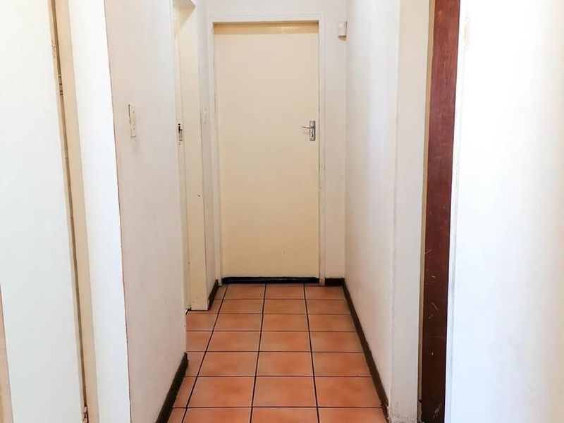 A functional interior hallway featuring tiled flooring and multiple doorways leading to various rooms within the home.