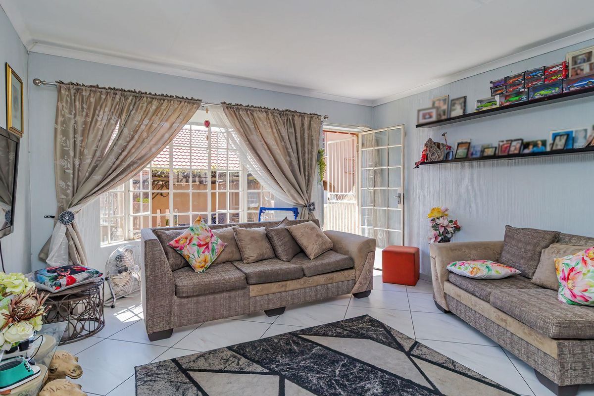 A bright living room featuring tiled flooring, coving, and direct access to the exterior through a security gate and french doors.