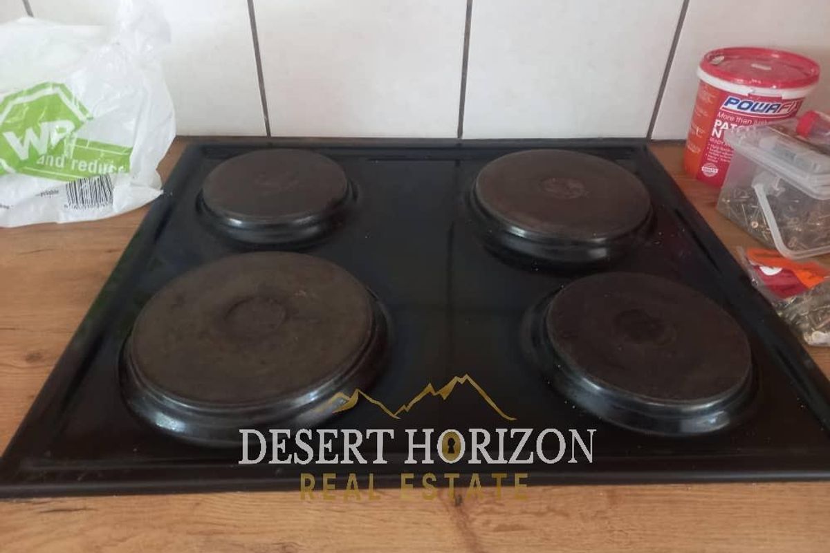 A four-plate electric hob set into a wooden countertop with tiled splashback.