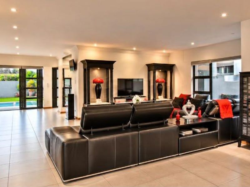 Spacious open-plan living area featuring tiled floors, recessed lighting, and built-in display cabinetry, with direct access to the outdoor pool area.