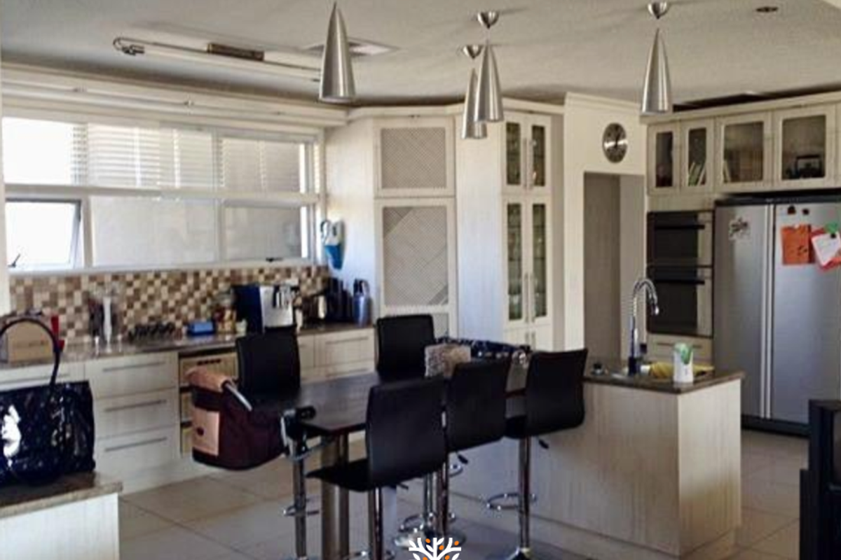 Spacious kitchen featuring built-in cabinetry, a central island with breakfast bar seating, integrated oven, and tiled flooring.