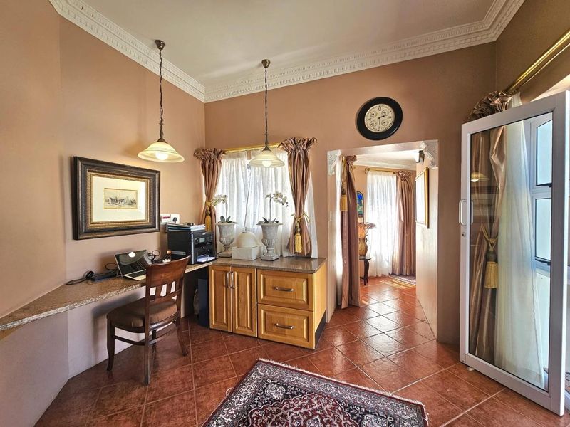 A functional home office space featuring built-in desk and cabinetry, tiled flooring, and decorative crown molding.