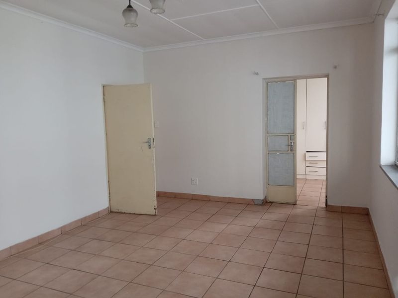 An empty bedroom featuring tiled flooring and built-in cupboards, providing a blank canvas for renovation or staging.