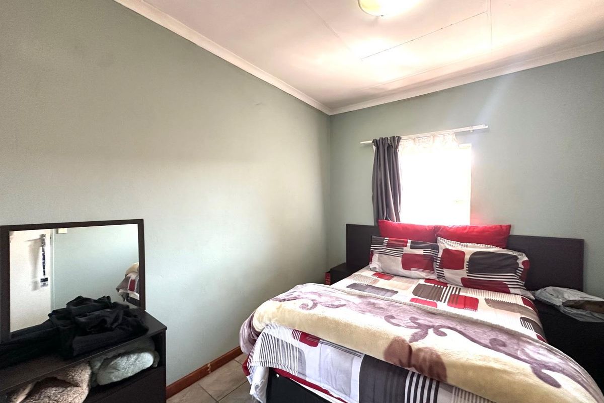 A standard bedroom featuring tiled flooring, neutral wall paint, and a ceiling-mounted light fixture.