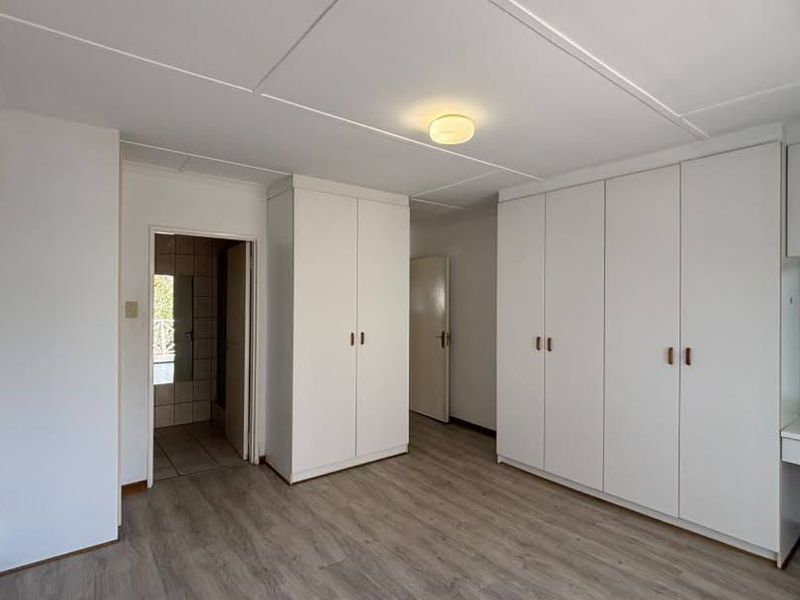 Spacious bedroom featuring extensive built-in cabinetry, a dedicated vanity area, and modern laminate flooring.