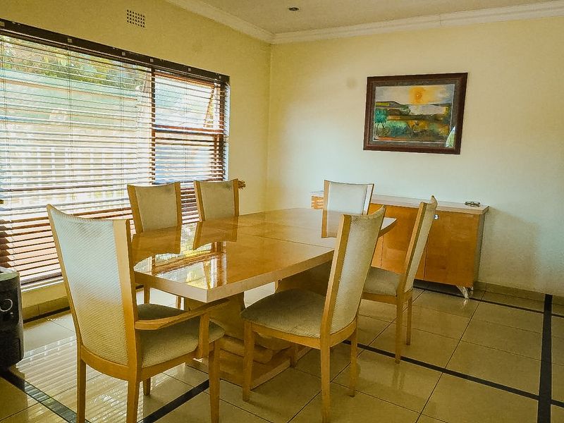 A dining room featuring tiled flooring, coved ceilings, and large windows fitted with venetian blinds, providing a functional space for family meals.