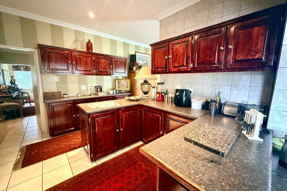 A functional kitchen featuring dark wood cabinetry, granite-look laminate countertops, and tiled splashbacks, offering a traditional aesthetic with ample storage space.
