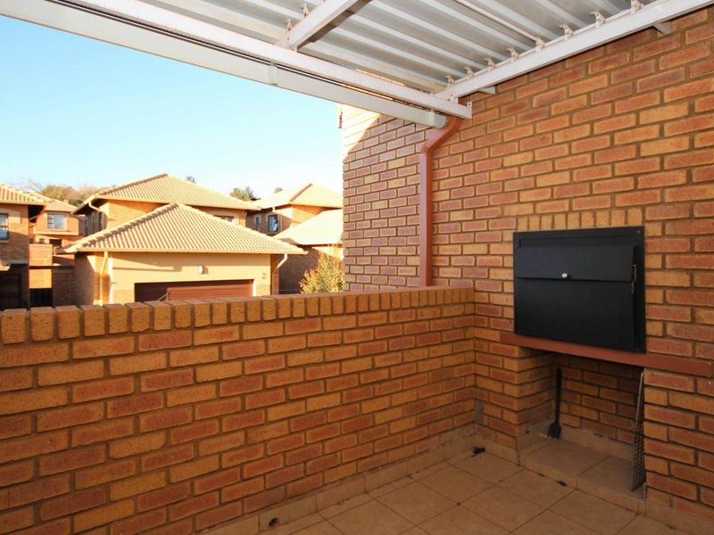 Covered balcony featuring a built-in brick braai and tiled flooring, offering a functional outdoor entertainment space.