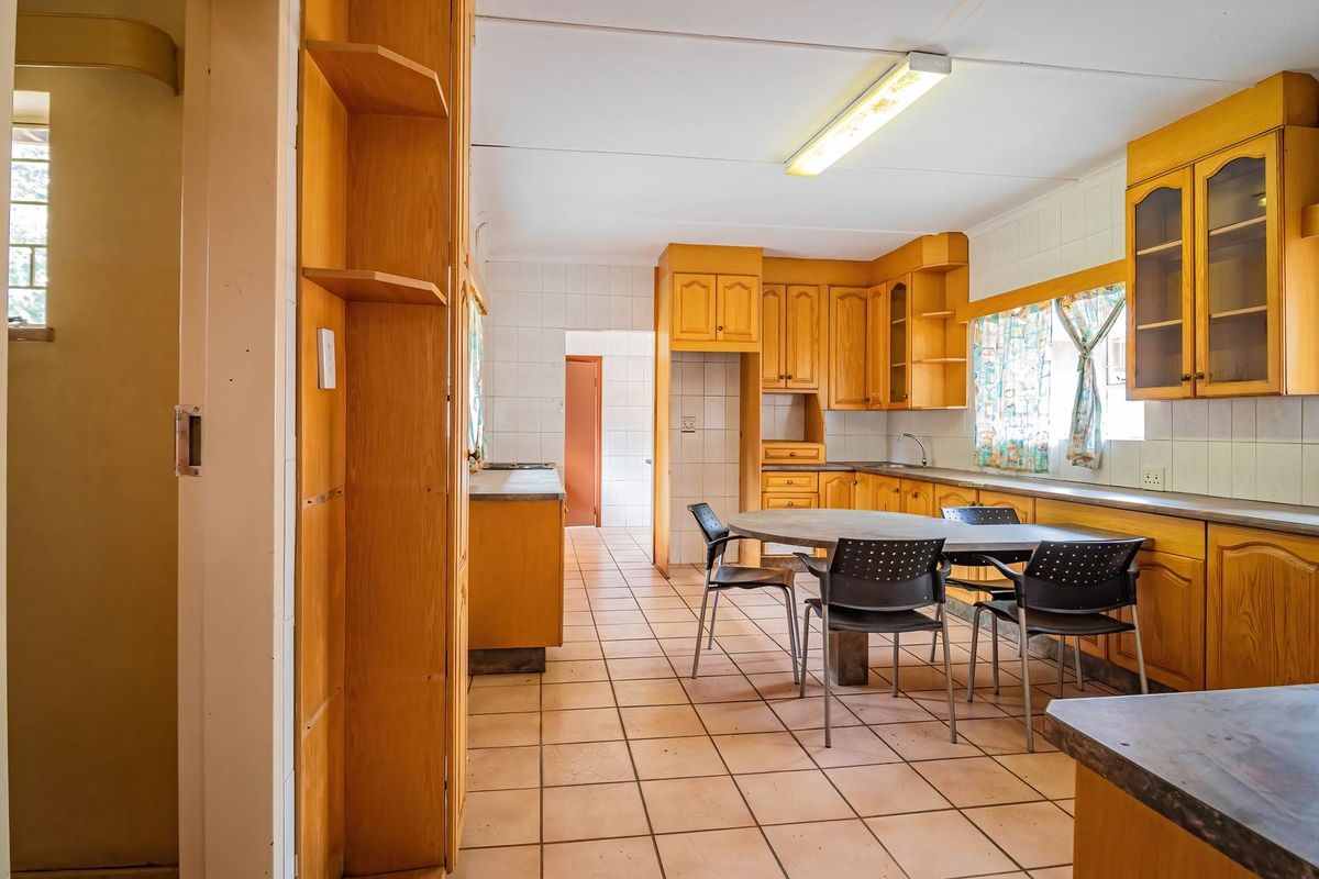 A spacious, dated kitchen featuring extensive wooden cabinetry, tiled flooring, and a tiled backsplash, offering significant potential for a modern renovation.