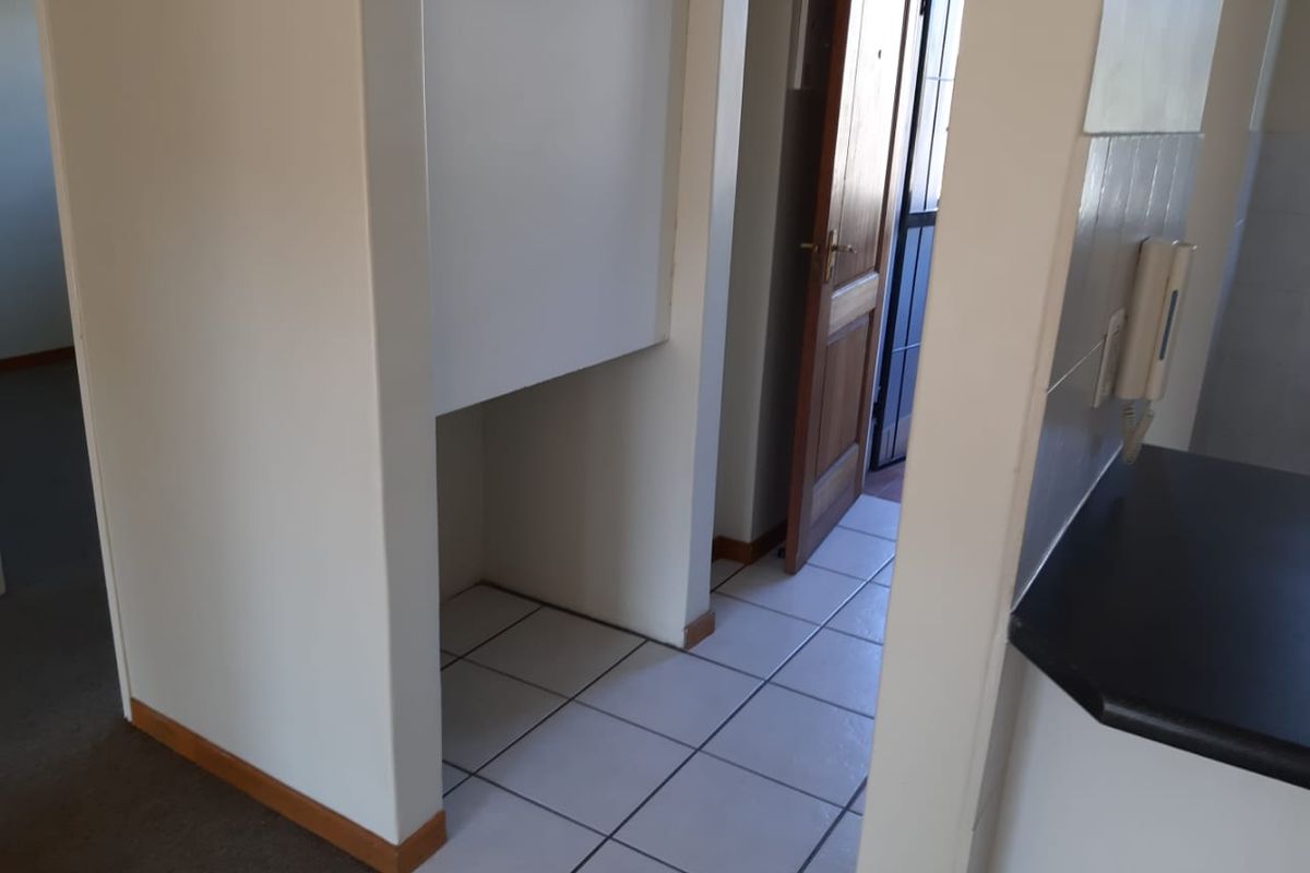 A functional hallway area featuring tiled flooring and a timber entrance door, providing access to the main living spaces.