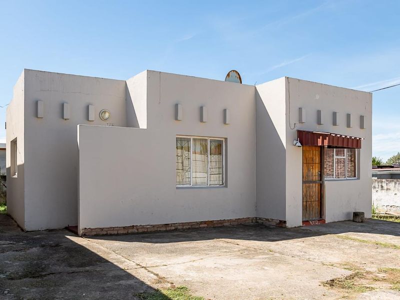 Front elevation of a single-story house featuring a concrete driveway, security gate, and exterior awning.