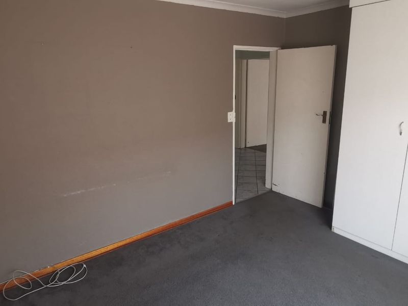 An empty bedroom featuring built-in cupboards, carpeted flooring, and neutral wall tones, offering a blank canvas for potential updates.