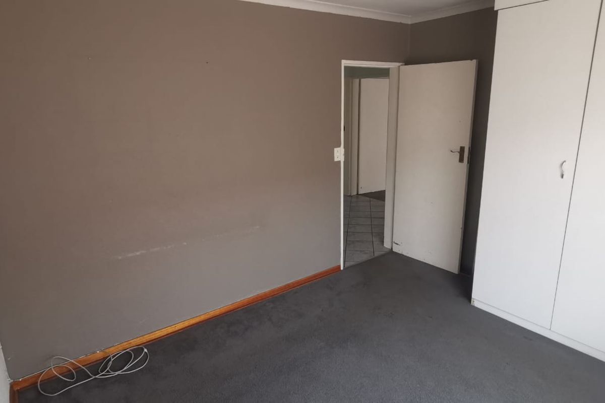 An empty bedroom featuring built-in cupboards, carpeted flooring, and neutral wall tones, offering a blank canvas for potential updates.