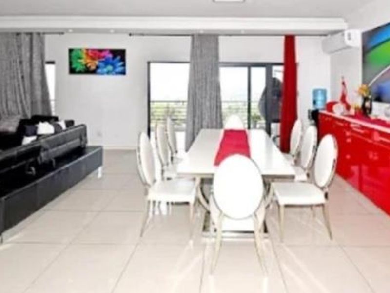 Spacious open-plan living and dining area featuring tiled flooring, recessed lighting, and direct access to an outdoor balcony through sliding glass doors.