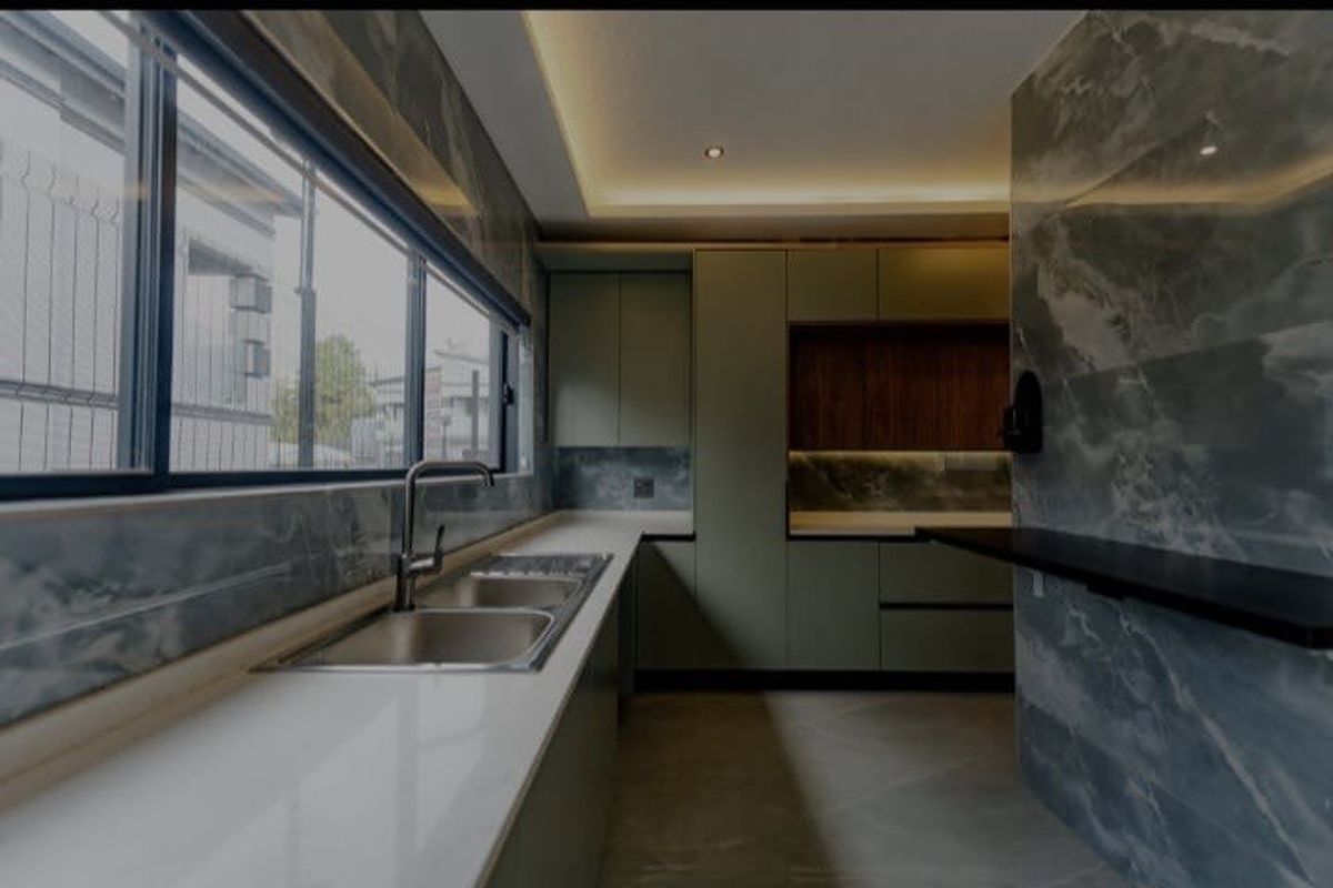 Modern kitchen featuring sleek green cabinetry, stone countertops, double bowl sink, and elegant marble-effect wall tiling with integrated recessed lighting.