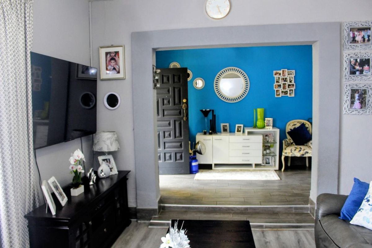 A view from the living area into an adjacent room, featuring tiled flooring, a raised threshold, and a bold blue accent wall.