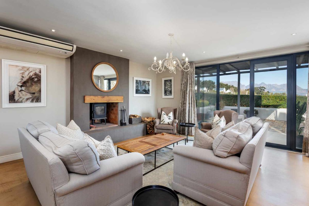 A well-appointed living room featuring a central fireplace with a timber mantel, polished concrete floors, and large sliding doors opening to an outdoor area.