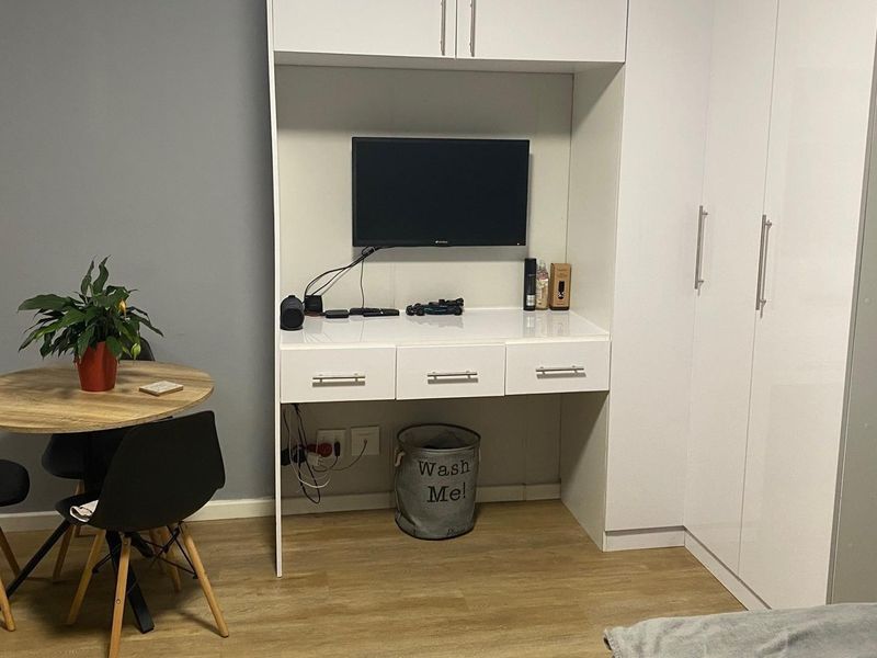 A bedroom featuring a built-in white wardrobe and integrated desk unit with laminate flooring.